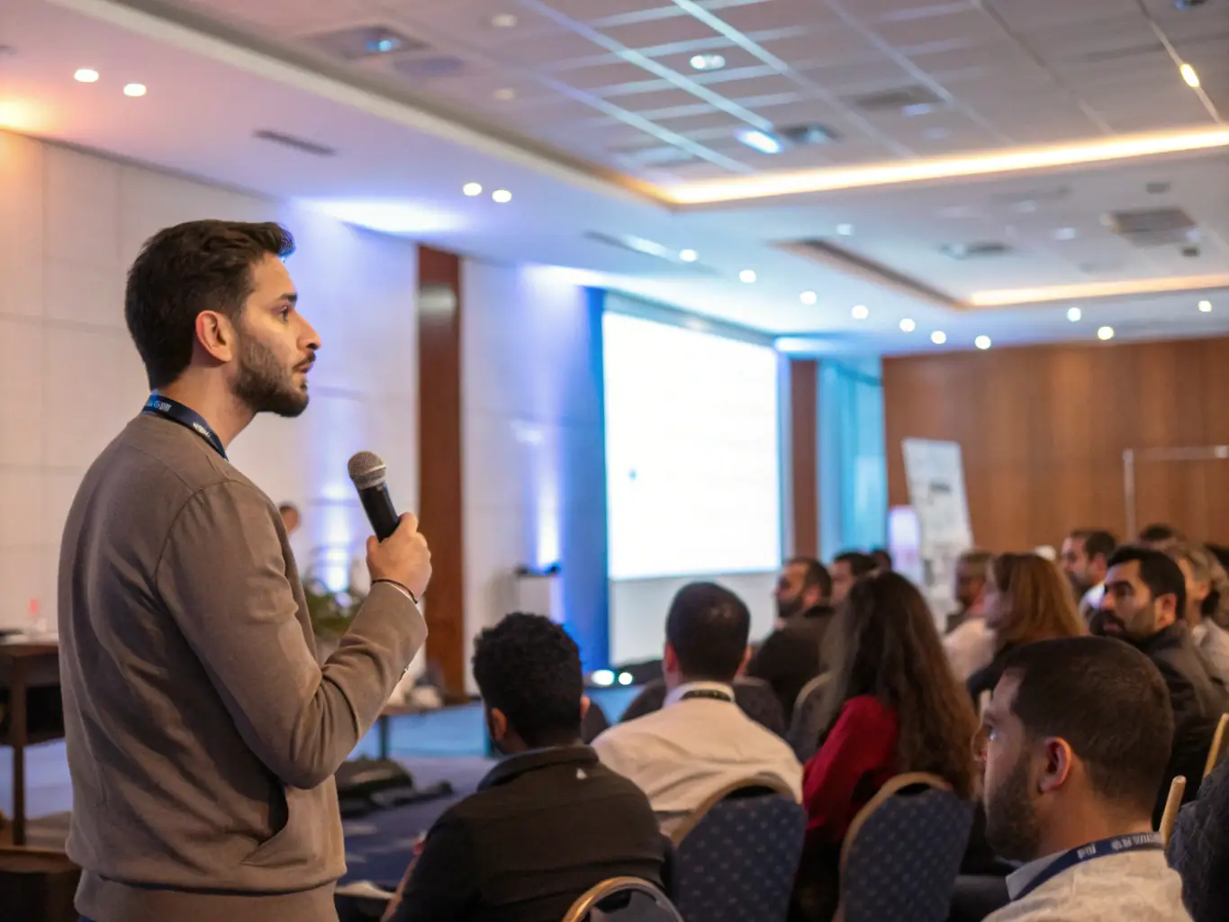 A conference setting with speakers and attendees, representing the knowledge-sharing and networking opportunities provided by LA COUR DES ARTS.